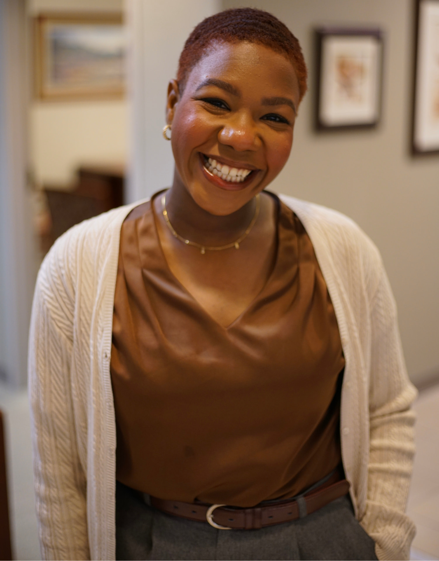 Portrait of Sasha Bowers smiling, wearing a white cardigan and gold necklace
